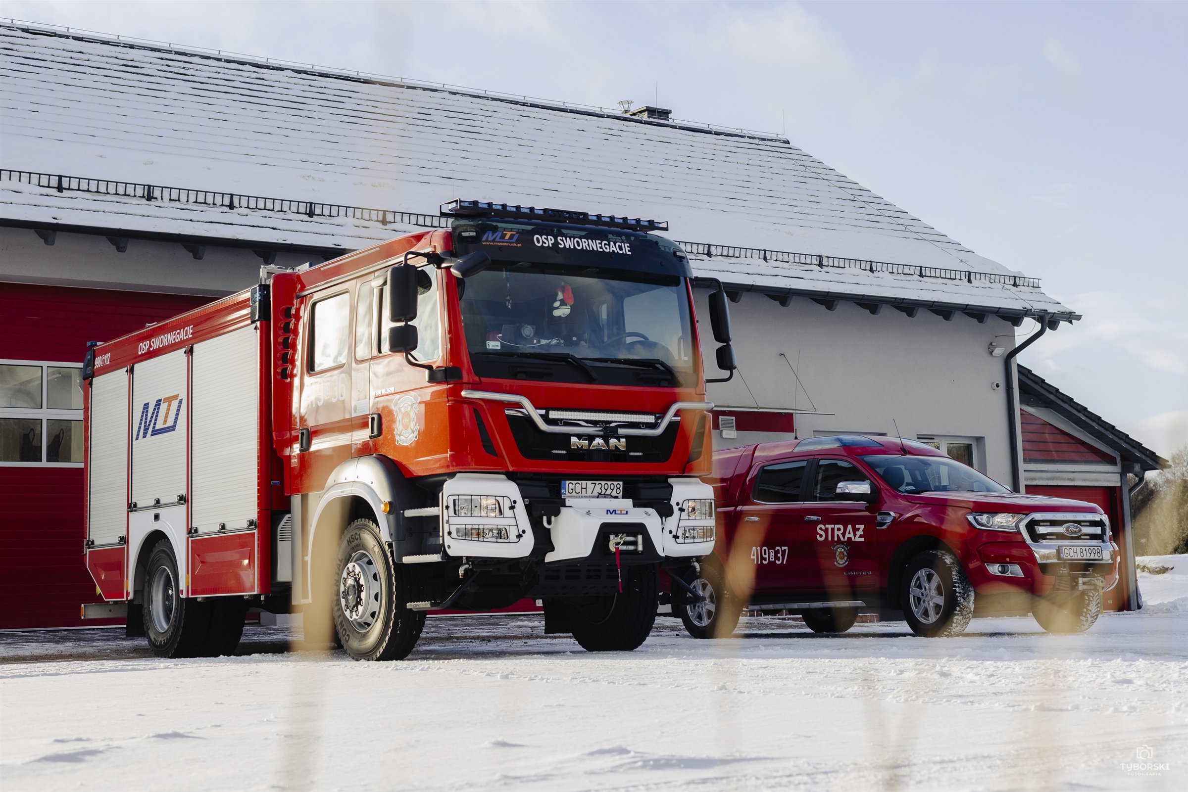 Dwa czerwone samochody OSP Swornegacie przed remizą